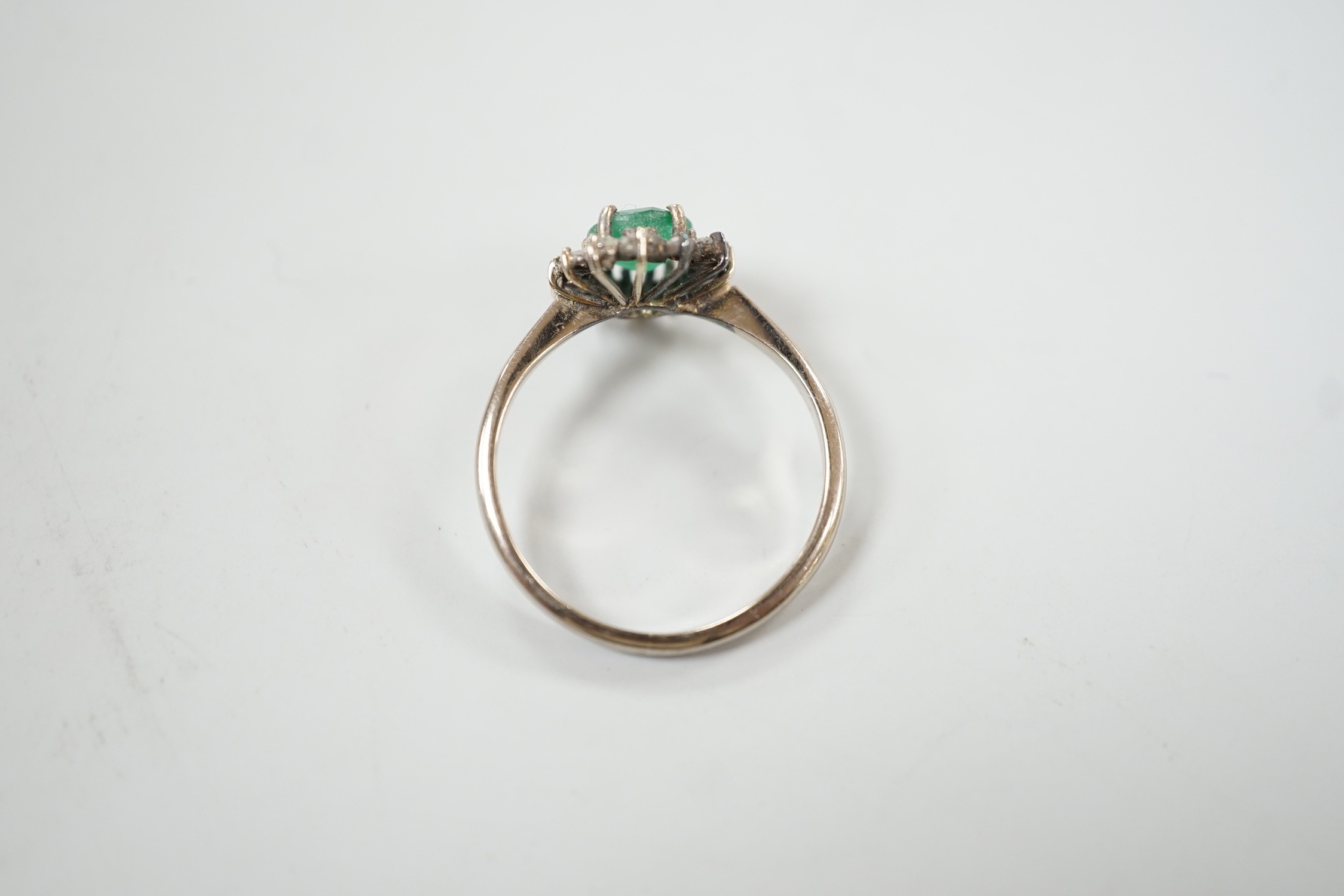 An 18ct, emerald and diamond set oval cluster ring, size O/P, gross weight 3.2 grams.